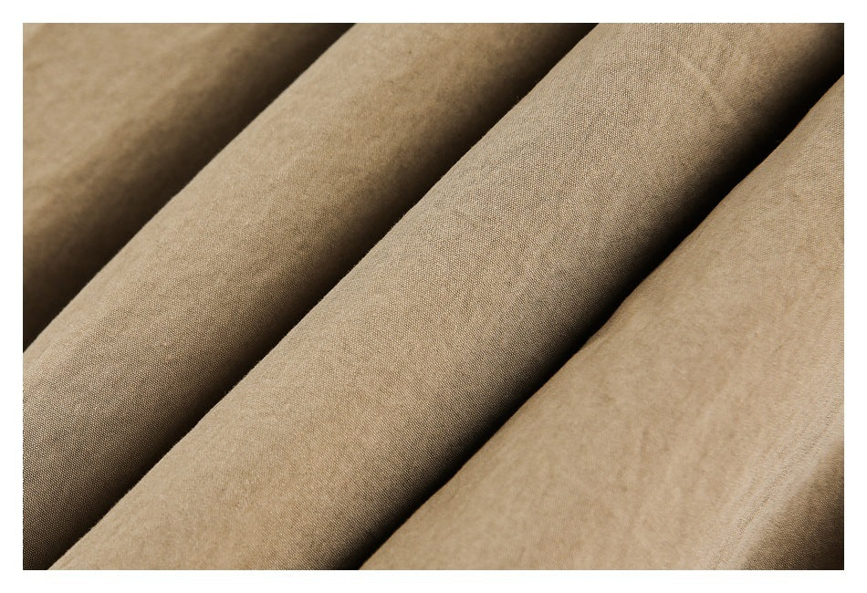 Close-up of tan fabric arranged in overlapping folds, showing its surface texture.