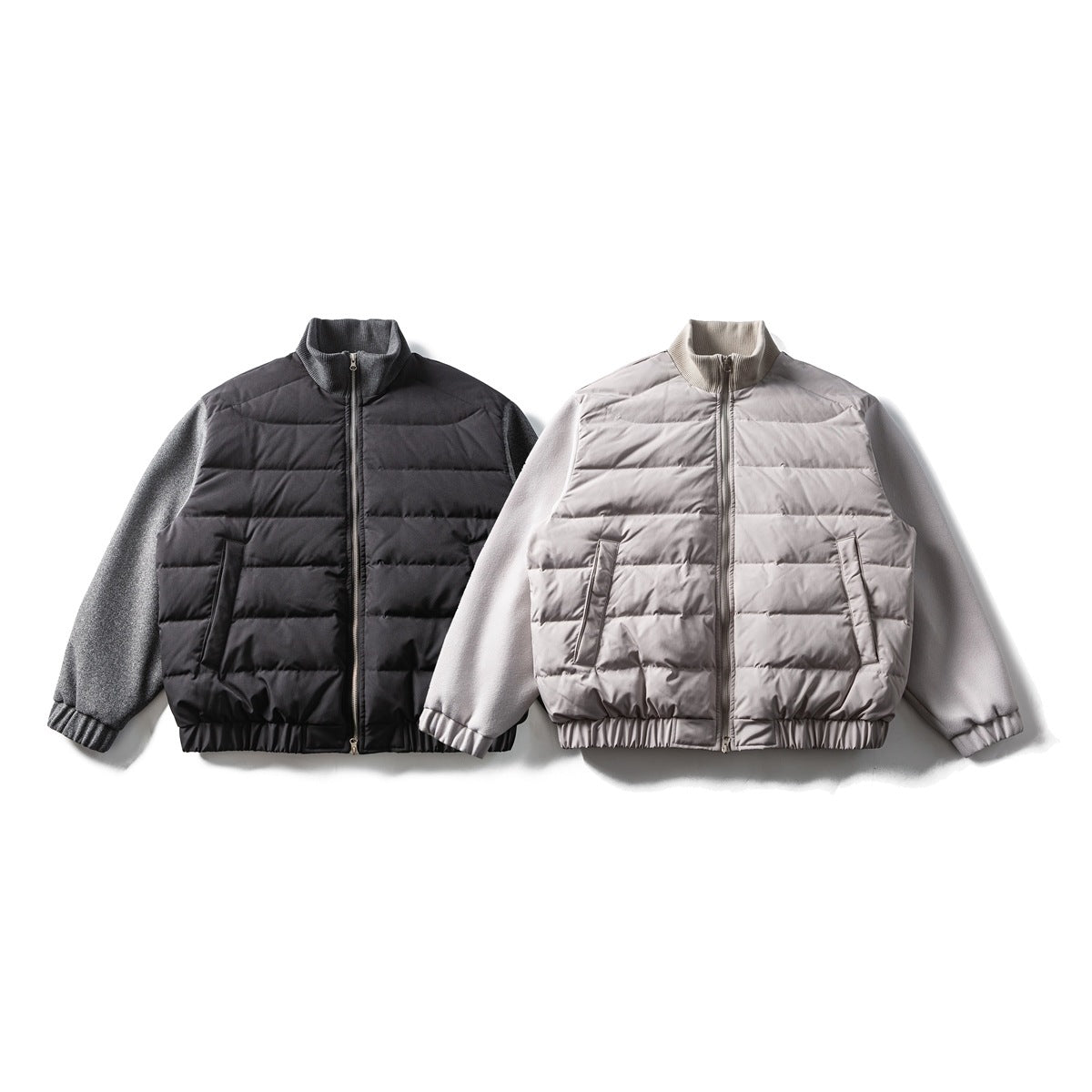 Front views of two zip-front jackets: one black and gray, the other light gray, with quilted bodies and knit sleeves.