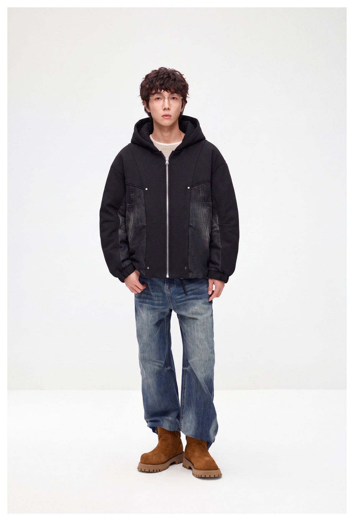 Model wearing a black hooded zip jacket with dark denim side panels, blue jeans and brown boots.