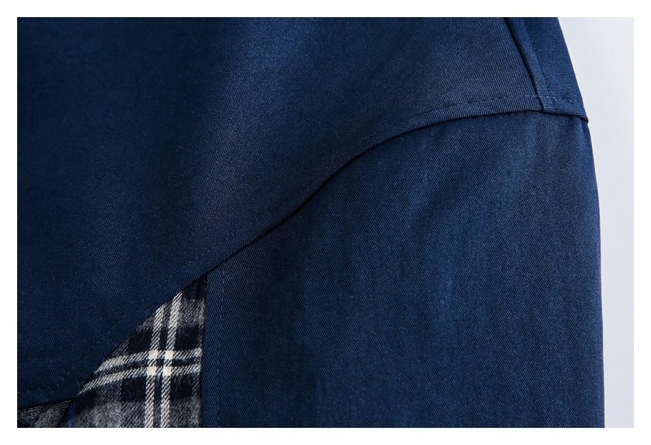 Close-up of navy jacket fabric, curved seam and a small section of plaid inset.