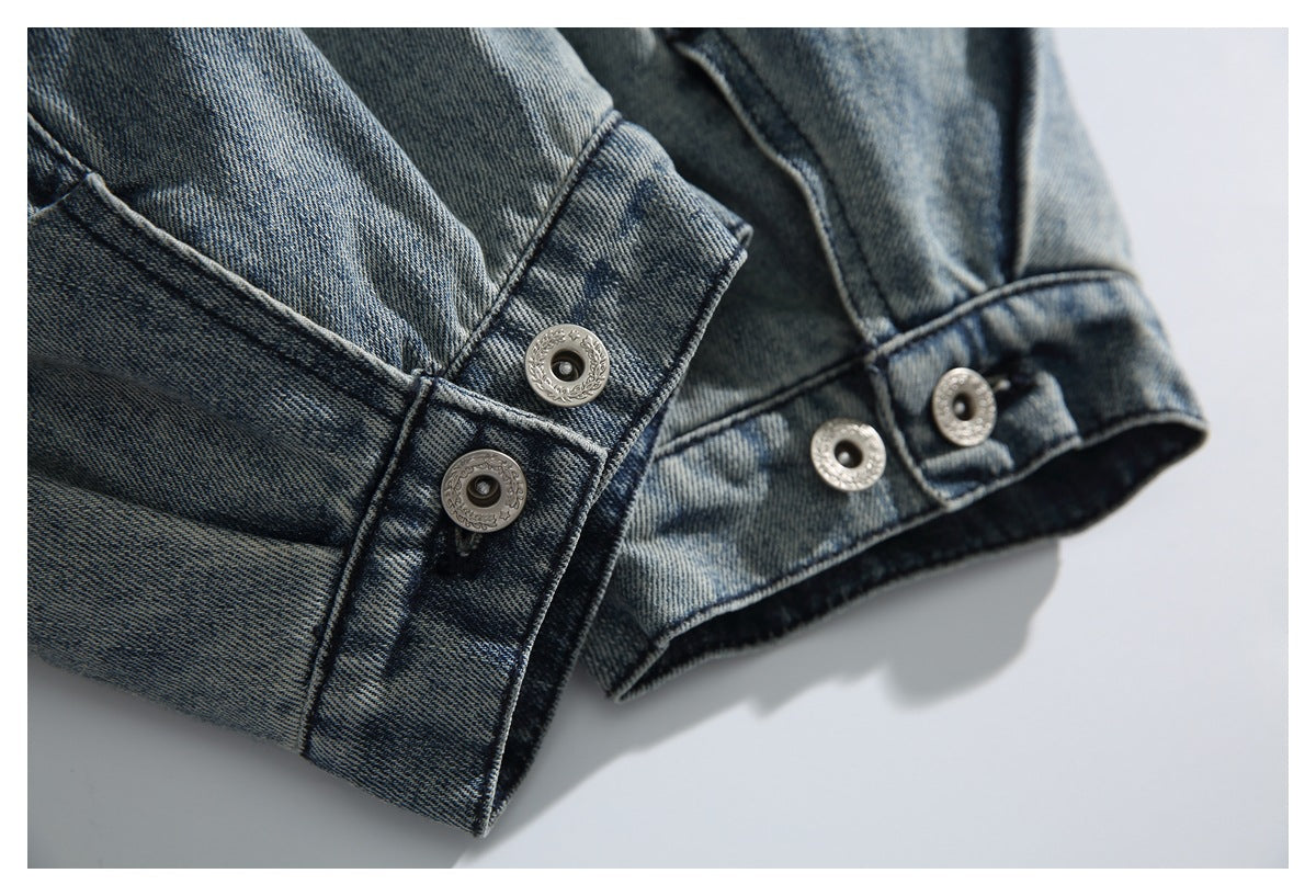 Close-up of a washed denim jacket cuff with multiple decorative metal snap buttons.
