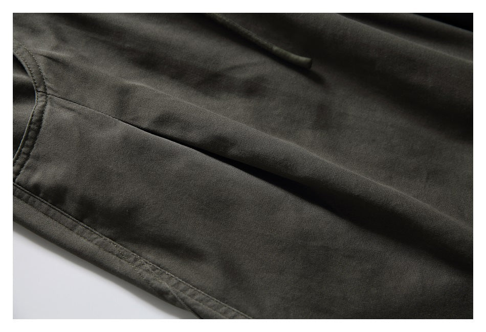 Close-up of dark olive-gray pant leg with a stitched seam and folded fabric.