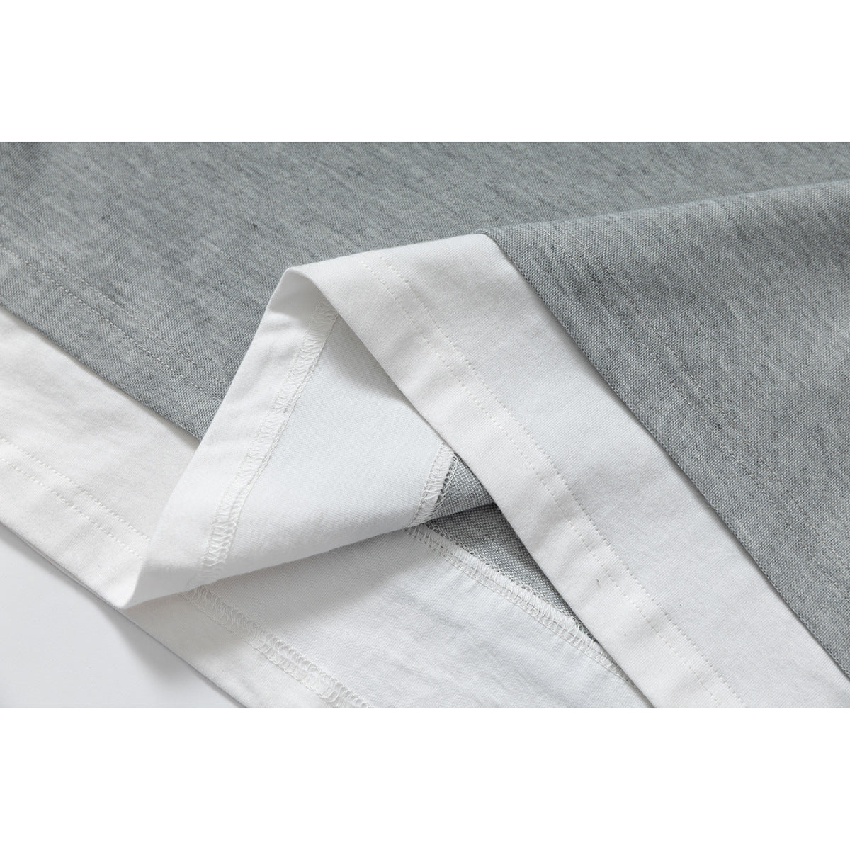 Close-up of the shirt’s gray body and white hem, with the hem folded to show the stitching.