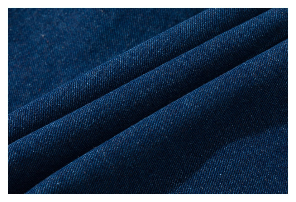 Extreme close-up of dark blue denim fabric folded to show its diagonal weave.