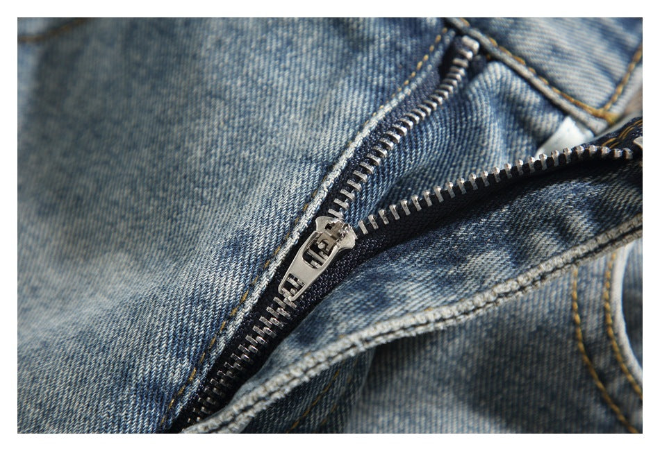 Close-up of the metal zipper and fly stitching on washed blue jeans.