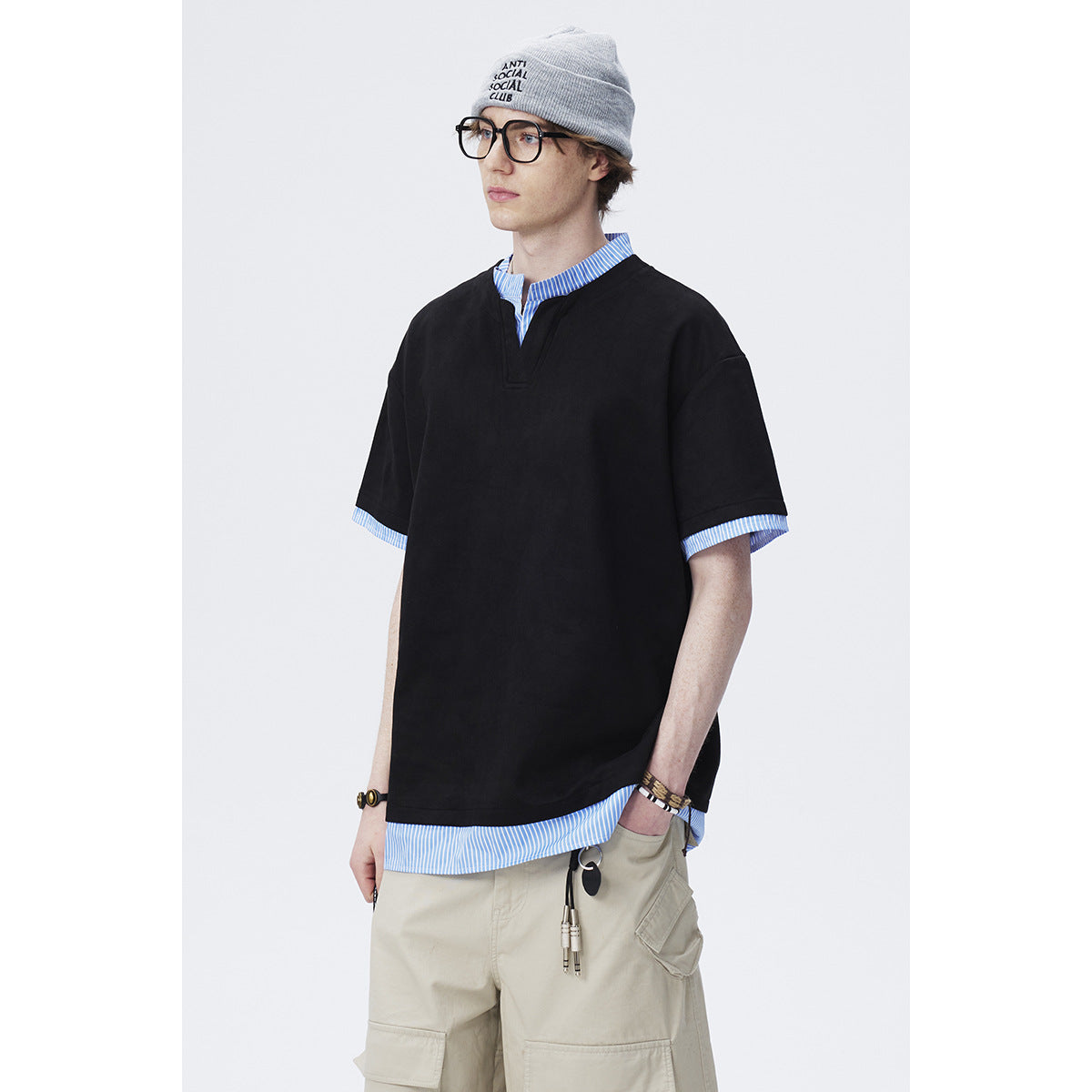 Model wearing an oversized black short-sleeve top with a notched neckline and blue striped shirt details.