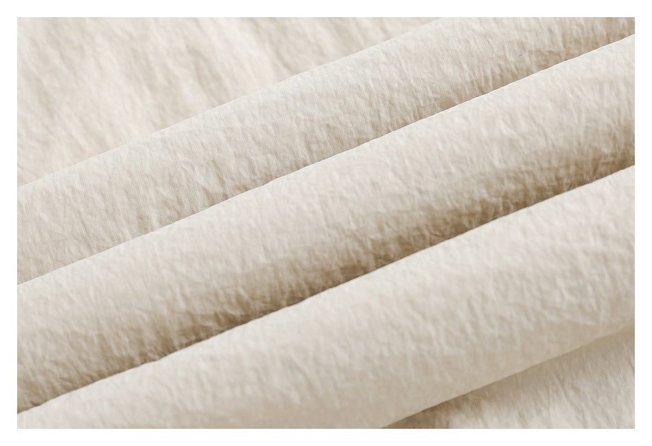 Extreme close-up of softly crinkled light beige fabric arranged in overlapping folds.