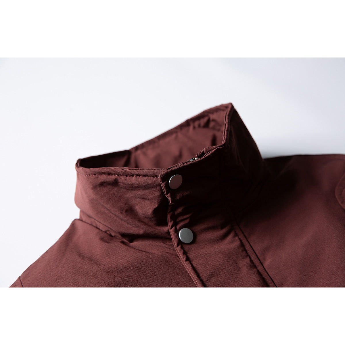 Close-up of the burgundy jacket's high collar and snap-button front closure.