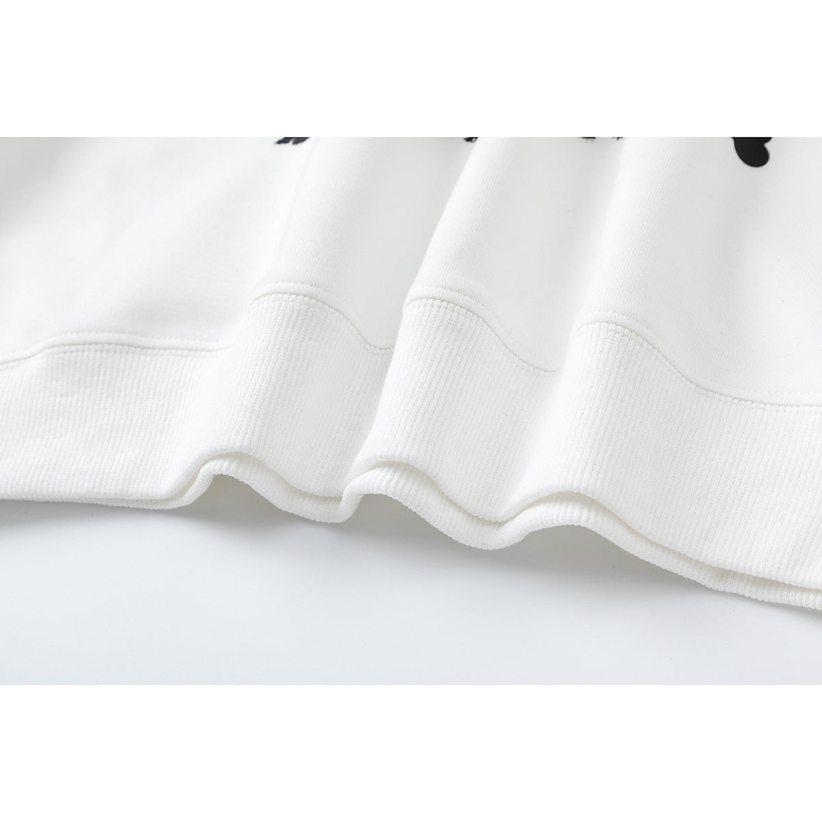 Close-up of the white sweatshirt's wide ribbed hem and stitched seam.