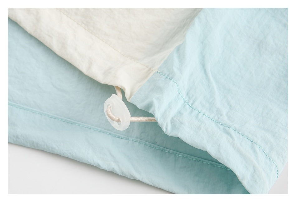 Close-up of ivory and pale blue bedding fabric with a cord and plastic fastening.