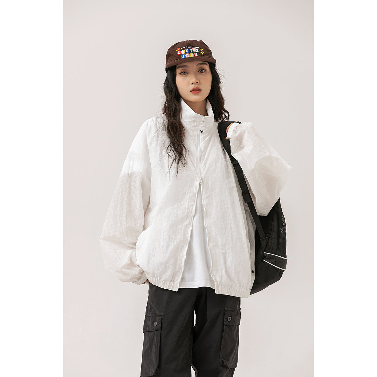 Model wearing a loose white zip-front jacket with a high collar, elastic cuffs and hem.