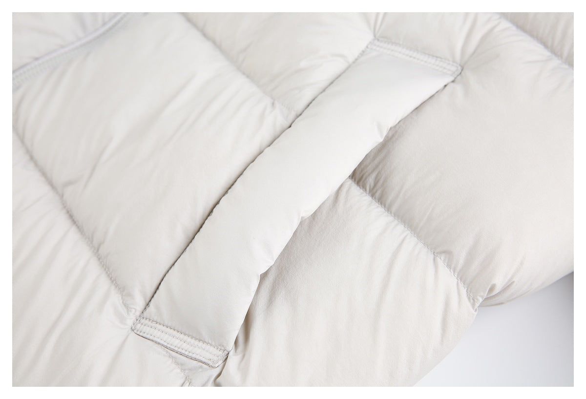 Close-up of an off-white padded jacket showing quilted panels and a stitched fabric tab.