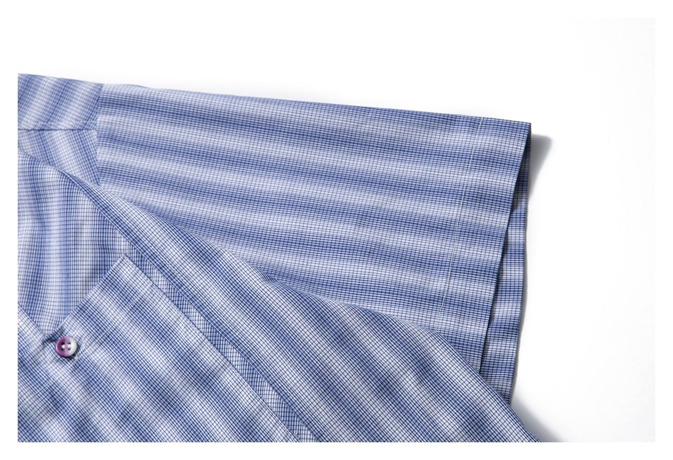 Close-up of a blue-and-white fine-check shirt with a button and folded fabric.
