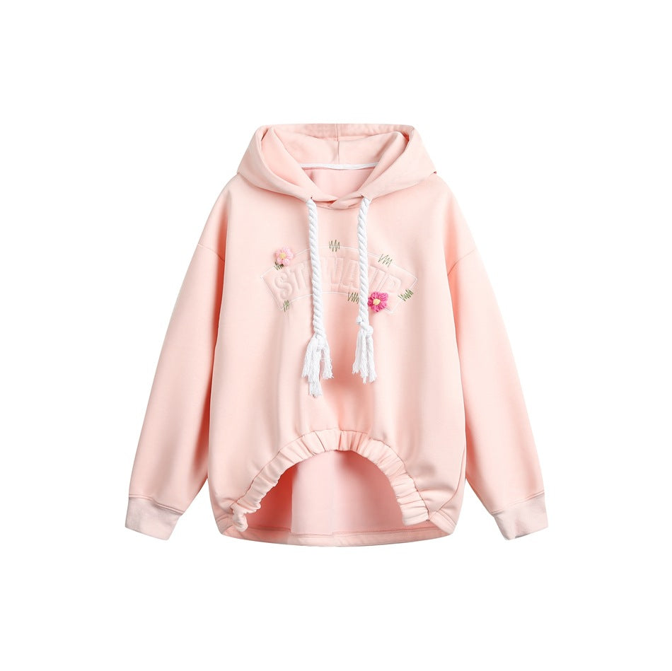Pink pullover hoodie with white rope drawstrings, embroidered arched lettering, two small flowers and a gathered hem
