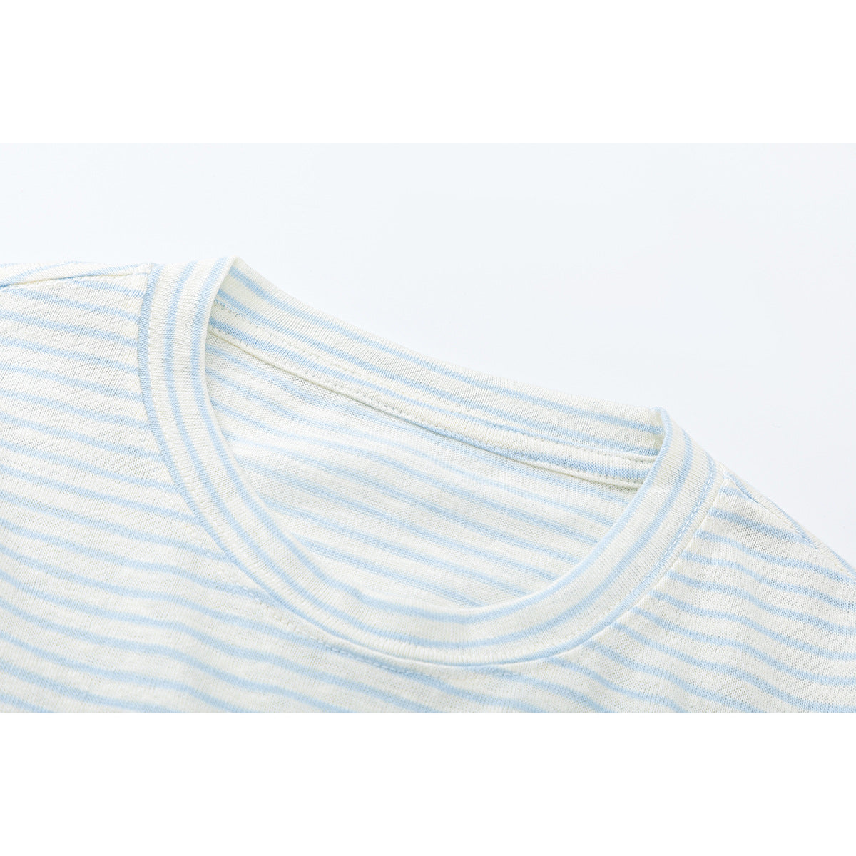 Close-up of a cream and pale blue striped shirt showing its crew neckline and shoulder seams.