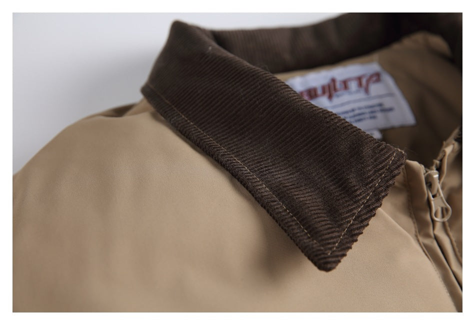 Close-up of a tan jacket with a dark brown corduroy collar, zipper pull and partly visible neck label.