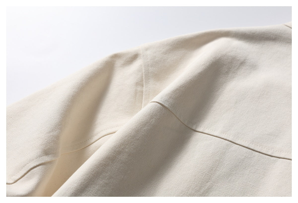 Close-up of an ivory jacket seam and textured fabric folds.