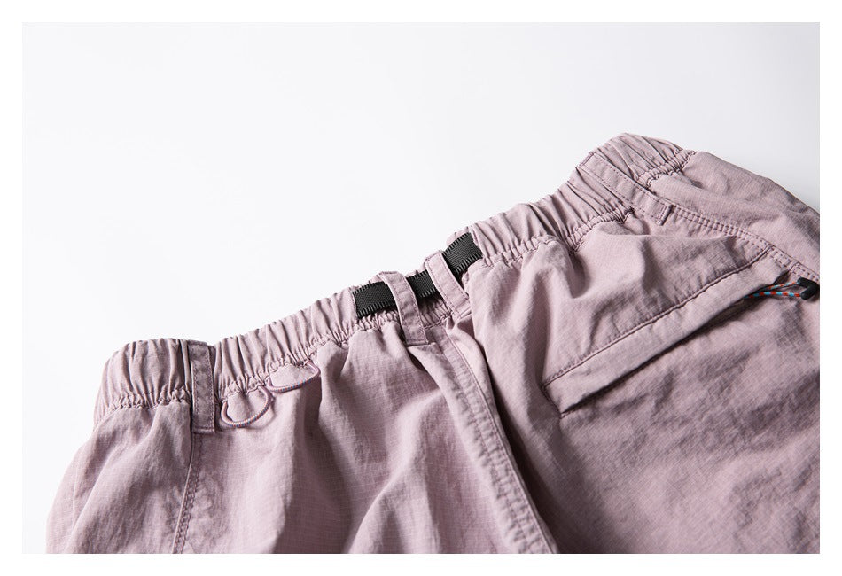 Close-up of dusty mauve shorts showing the elastic waistband, belt loops and black webbing belt.