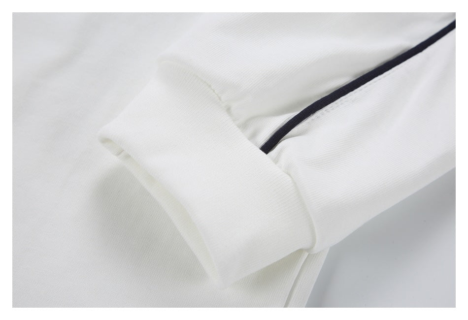 Close-up of a wide white ribbed cuff beside black piping on a white sleeve.