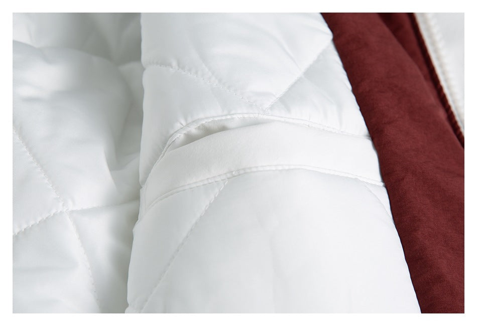 Close-up of white quilted jacket lining and stitched seams beside burgundy fabric.