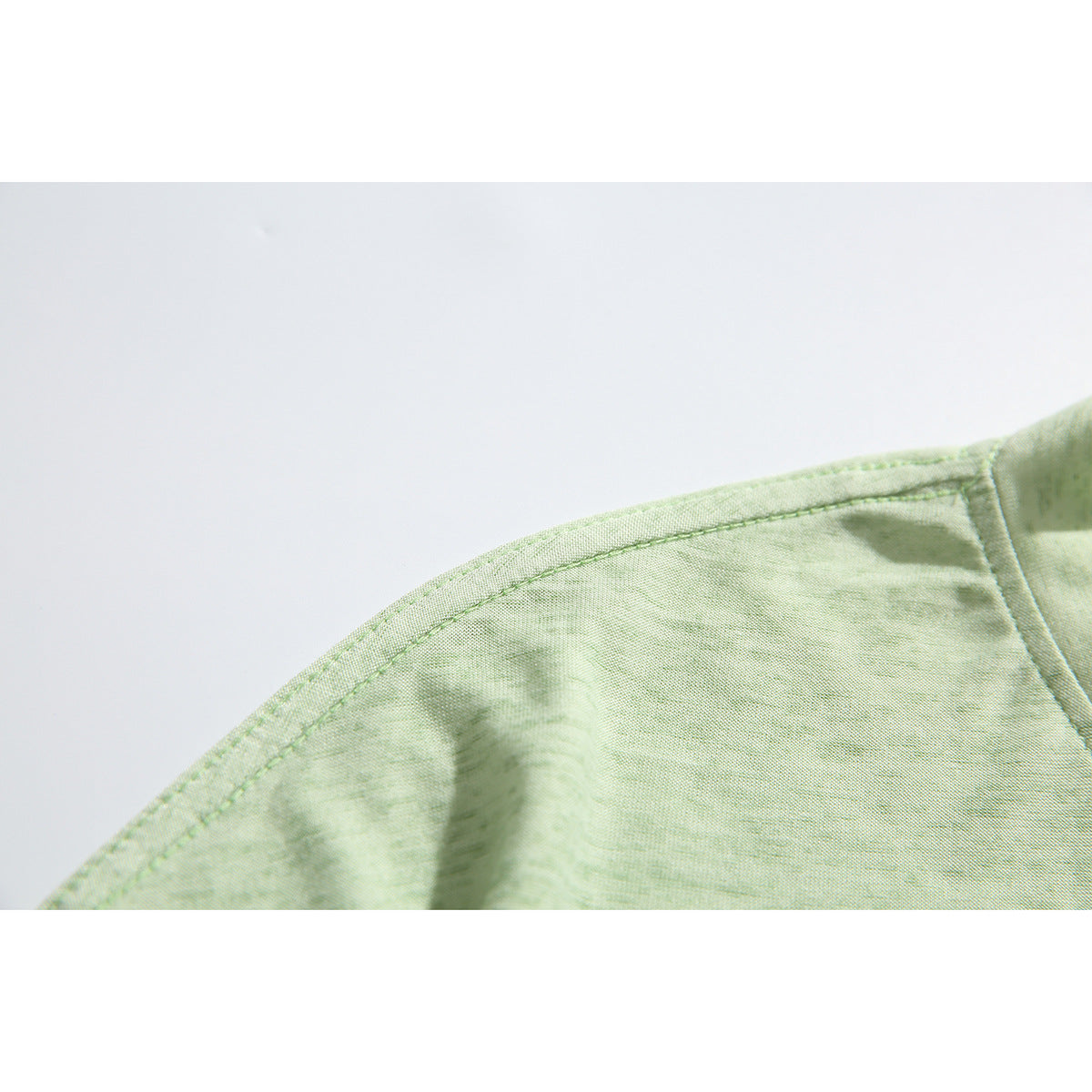 Close-up of the pale green shirt’s shoulder seam and stitching.