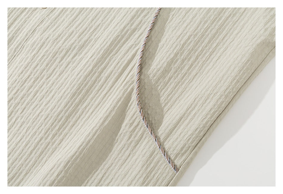 Close-up of cream textured shirt fabric with contrasting striped piping along a seam.