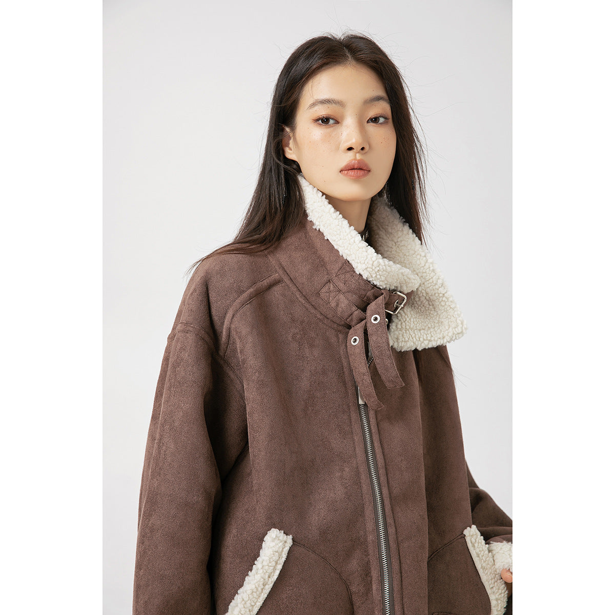 Close view of the brown jacket's cream fleece collar, buckle closure, zipper and fleece-trimmed pockets.
