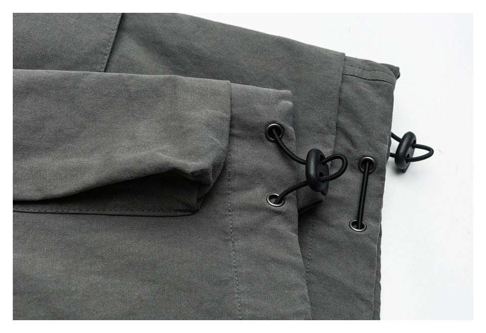 Close-up of charcoal gray garment panels with black cord toggles and metal eyelets.