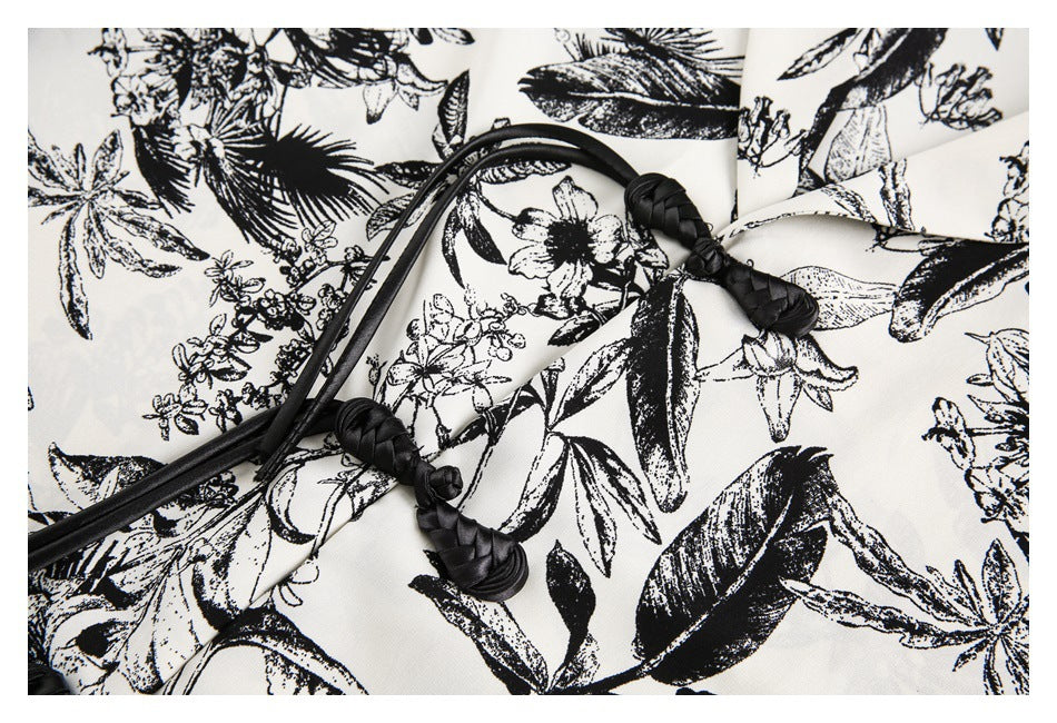 Close-up of black braided knotted closures on the ivory shirt with a black botanical print.