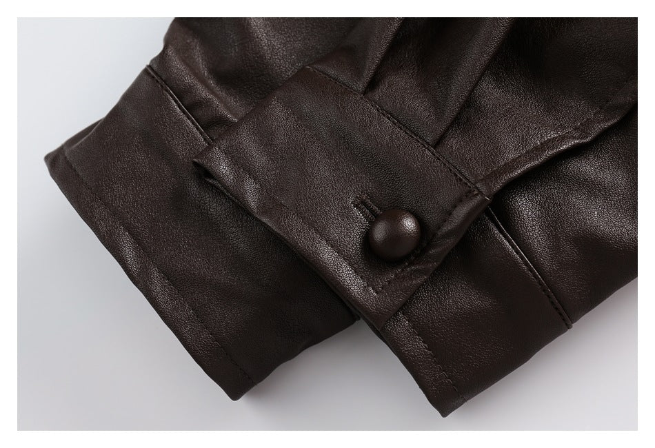 Close-up of a dark brown garment cuff with a matching button, stitched seams, and pebbled texture.