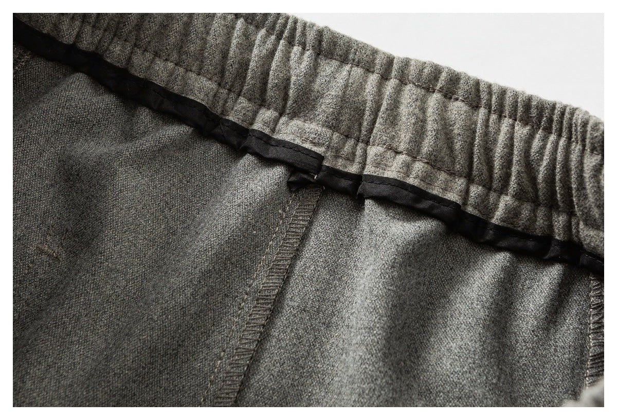 Close-up of a gray garment's gathered waistband, black binding, and interior seams.