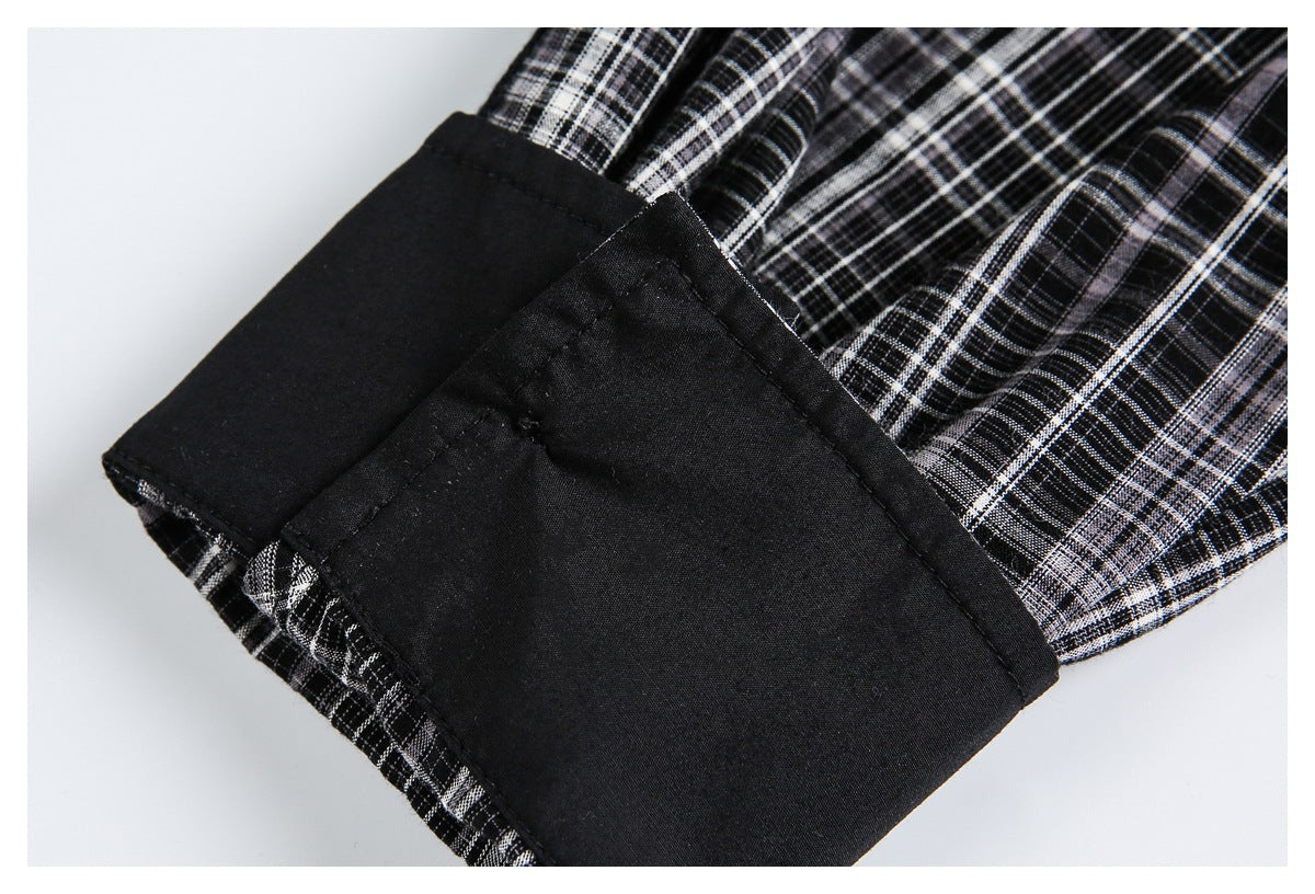 Close-up of a black cuff against black, white, and gray plaid fabric.