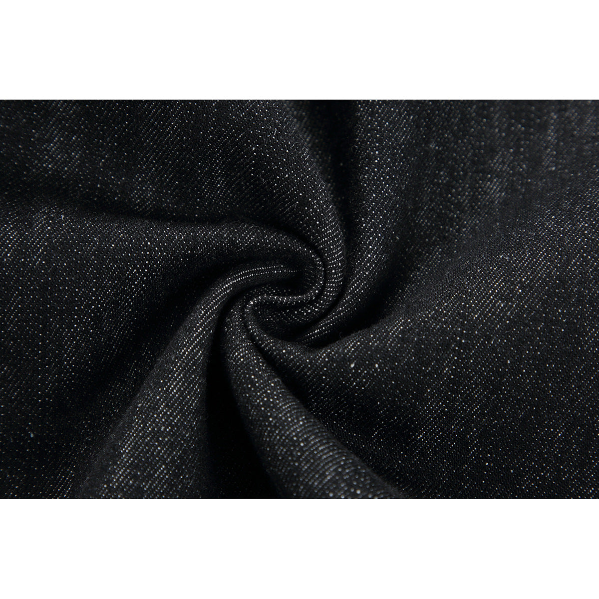 Macro view of dark denim fabric gathered into folds, showing its textured weave.