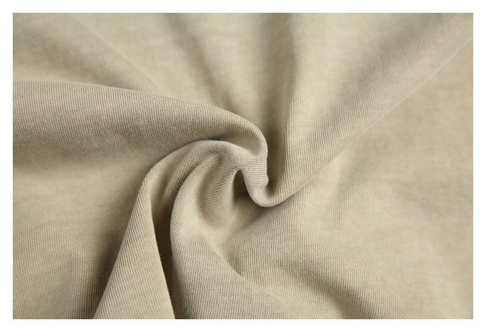 Close-up of beige fabric draped into soft folds, showing its fine textured surface.