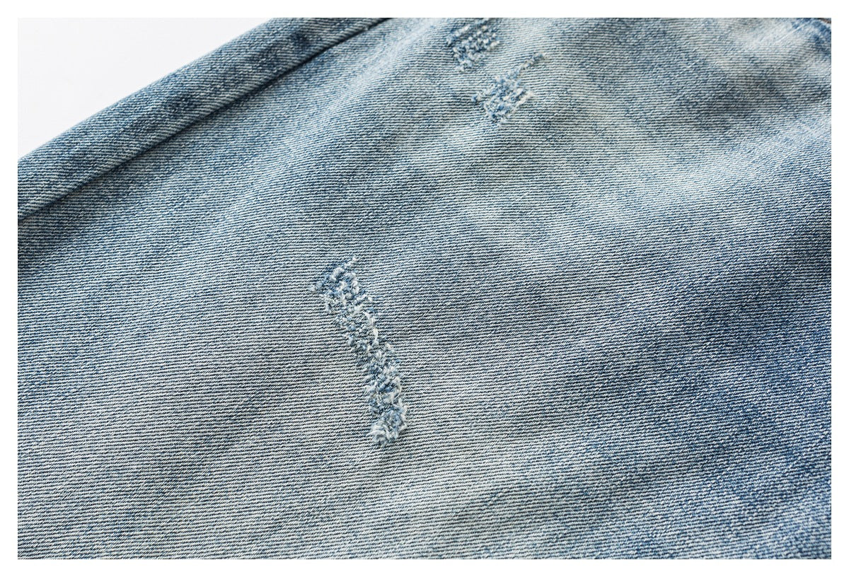 Close-up of blue denim with a small distressed patch and visible diagonal weave.
