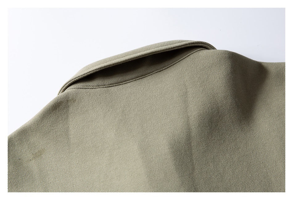 Close-up of the rounded neckline and stitched edge on a muted olive-beige garment.