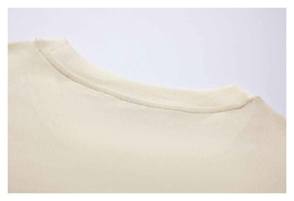 Close-up of the ivory garment's rounded neckline and stitching.