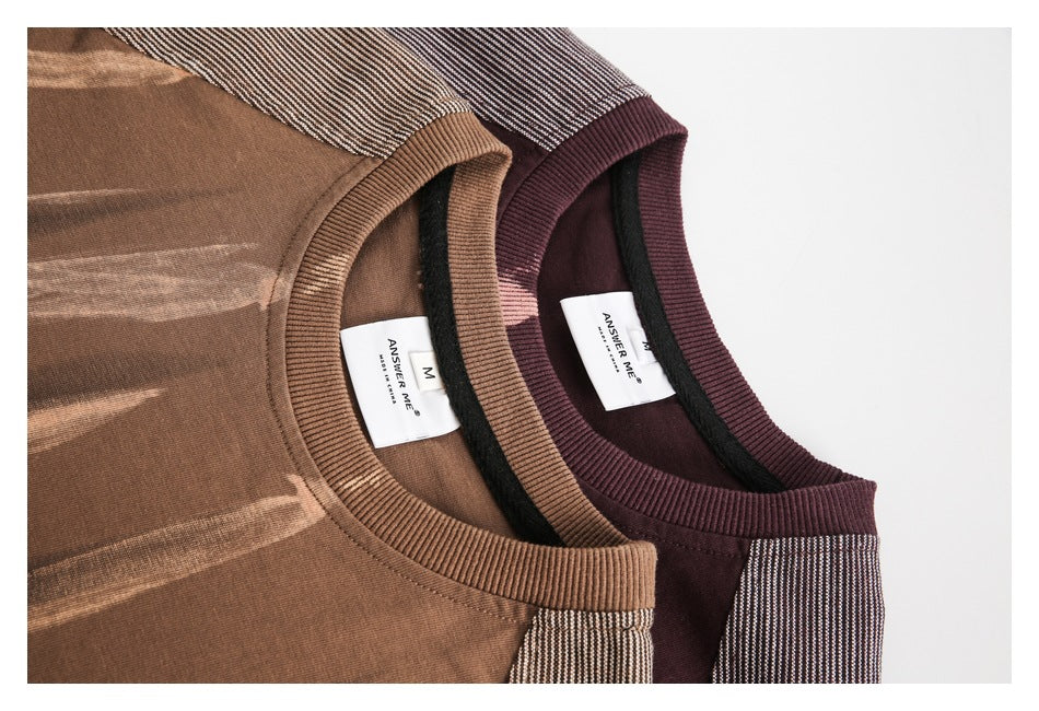 Close-up of brown and burgundy T-shirt necklines, ribbed collars, striped shoulders, and interior labels.