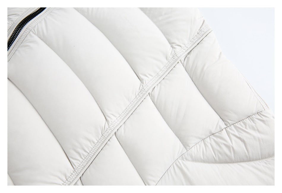Close-up of the white padded jacket's curved quilted panels and stitched seams.