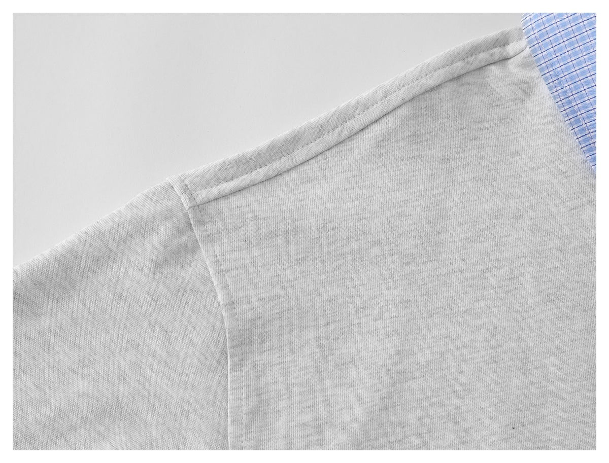 Close-up of the light gray shirt's shoulder seam, with part of its blue plaid collar visible.