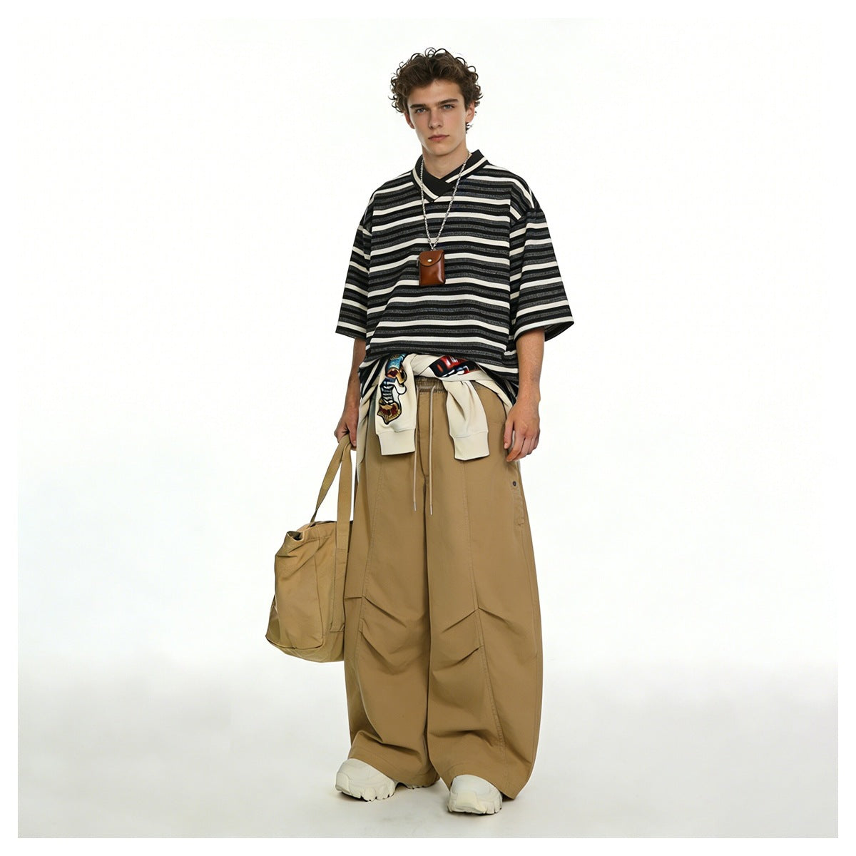 Model wearing oversized tan wide-leg trousers with a striped shirt and white sneakers.