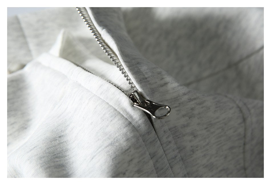 Close-up of a metal zipper and seam on a light gray heathered garment.