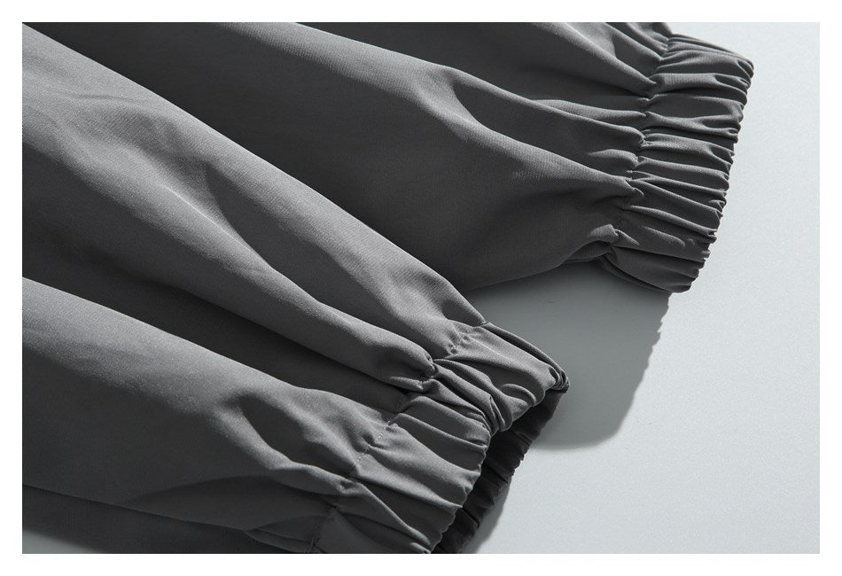 Close-up of charcoal pant legs with gathered elastic ankle cuffs.