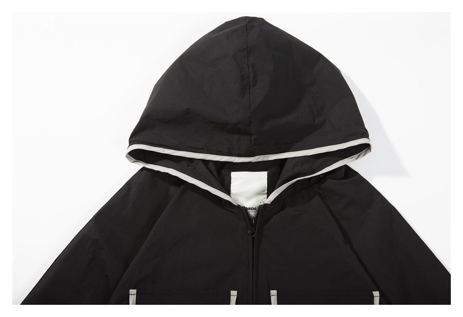Close-up of the black jacket's hood with pale contrasting trim and part of its front zipper.