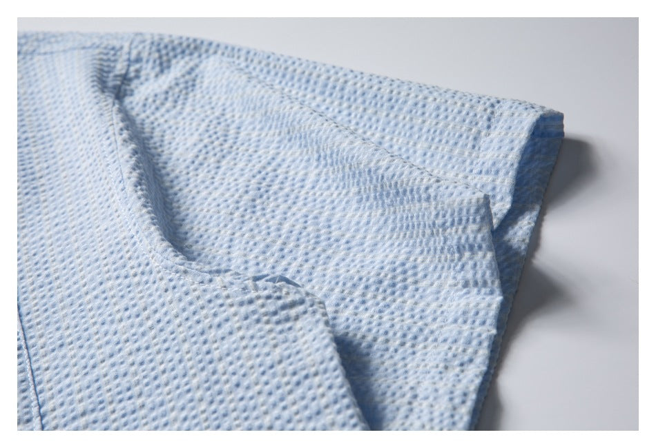 Close-up of the pale blue textured shirt showing a folded edge and stitched seam.