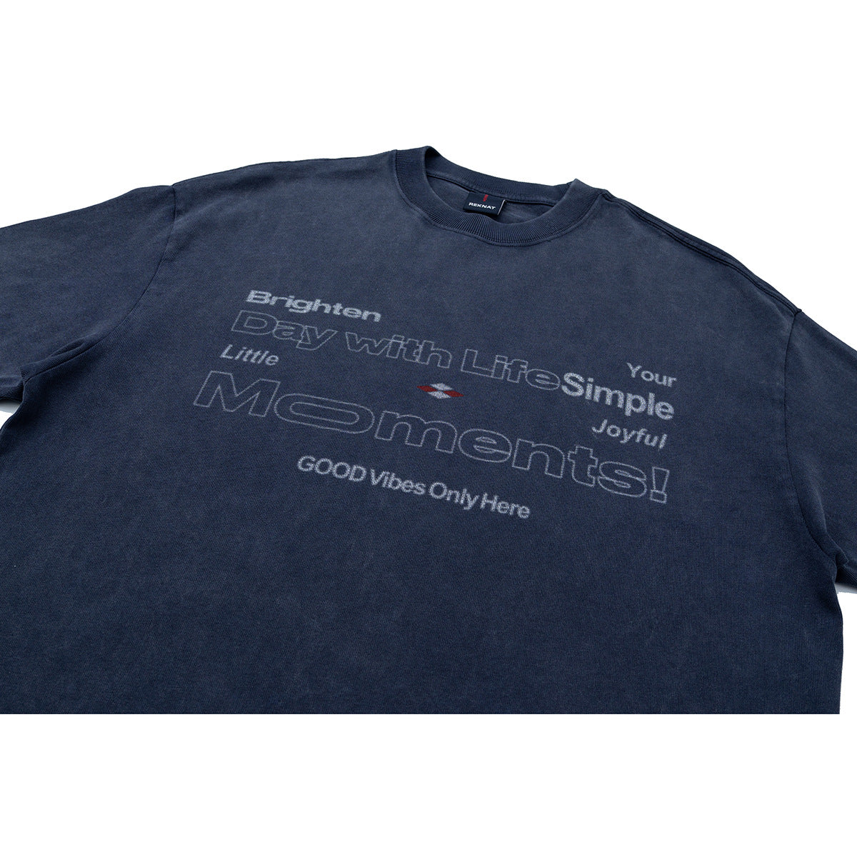 Close-up of a navy short-sleeve T-shirt front with pale outlined text and a small red-and-white graphic.