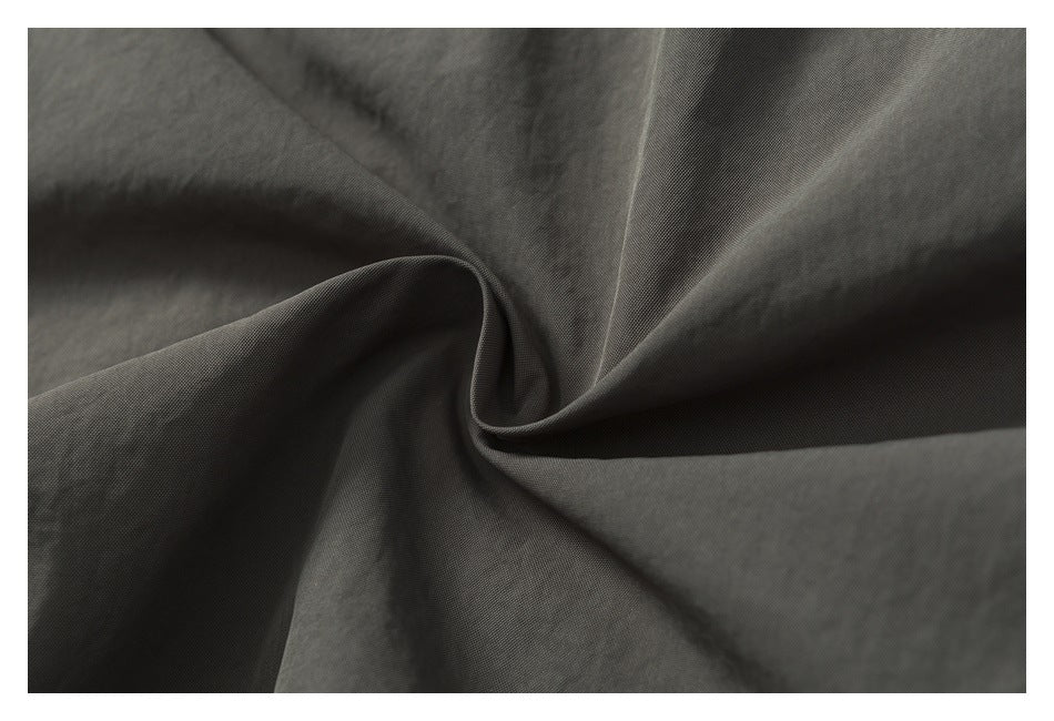 Macro view of charcoal-gray trouser fabric gathered into soft folds.