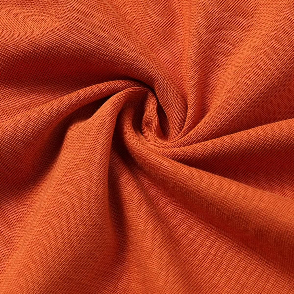 Close-up of orange knit fabric draped into soft folds.