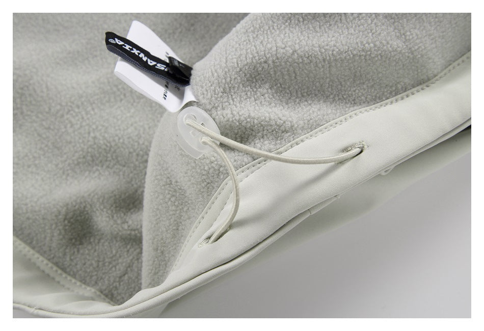 Close-up of a light gray garment interior with textured lining, a drawcord, and a fabric label.