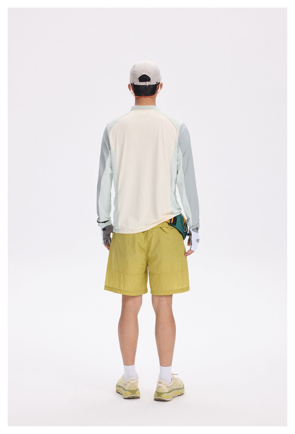 Model wearing the cream and sage green quarter-zip top with yellow shorts, back view